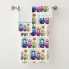 two towels hanging on a towel rack in front of a white wall with blue and purple designs