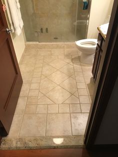 a bathroom with a walk in shower next to a white toilet and brown cabinetry