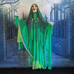 a woman dressed as a ghost in front of a backdrop with trees and tombstones