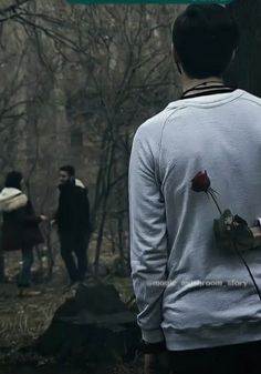 the back of a man's shirt that has a rose on it and people walking in the background