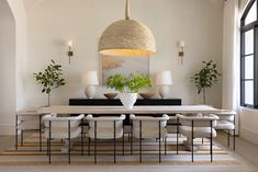 a dining room table with white chairs and plants