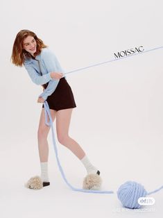 a woman in short skirt holding a ball of yarn and pulling it with a rope