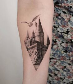 a black and white photo of a hogwarts castle tattoo on the right arm