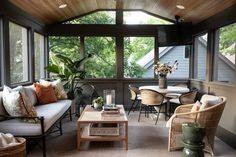 a screened porch with wicker furniture and plants on the table in front of it