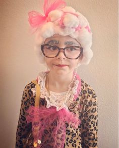 an older woman with glasses and a pink bow on her head wearing a leopard print top