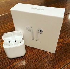 an open box with two apple airpods sitting next to it on a wooden table