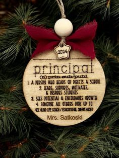 a wooden ornament hanging on a christmas tree with a red ribbon around it