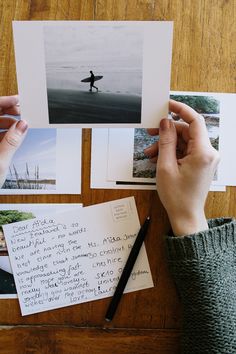 a person holding a surfboard on top of a wooden table next to post it notes