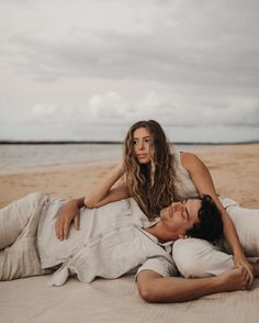 a man and woman laying on the beach together