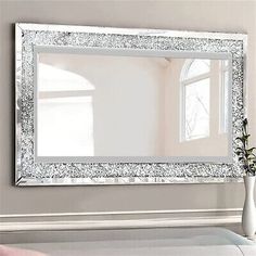 a white vase sitting on top of a table next to a large mirror in a room