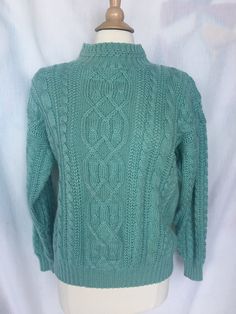 "Vintage 90s Cable Knit Sweater is a real classic! This super warm sweater has pretty patterned ribbed knit mock neck and shoulder pads that can be easily removed, held in place w/ Velcro. Sweater has interesting cable knit design and shows a beautiful sea foam green / aqua color. The cuffs and bottom of sweater have ribbed knit for extra warmth. Size label indicates a US ladies small. Please check measurements below for a proper fit. Good Vintage Condition Machine Washable Measurements taken w/ Retro Winter Polo Sweater With Ribbed Collar, Retro Polo Sweater With Ribbed Collar For Winter, 90s Knitted Winter Sweater, 90s Style Knitted Winter Sweater, 90s Winter Knitted Sweater, Retro Ribbed Knit Sweater, Vintage Knit Sweater With Ribbed Collar, Vintage Knit Polo Sweater For Winter, Retro Cable Knit Tops For Fall