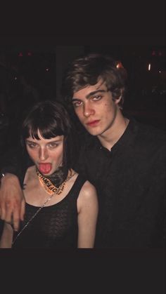 two people standing next to each other at a party with their mouths open and tongue out