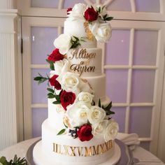 a three tiered wedding cake with red and white flowers