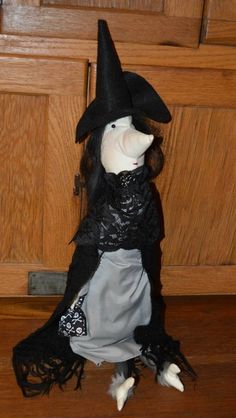 a stuffed animal wearing a witches hat and dress on the floor in front of a wooden door