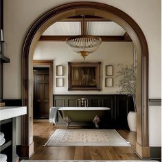 an arched doorway leads to a large bathroom with a tub and rug on the floor