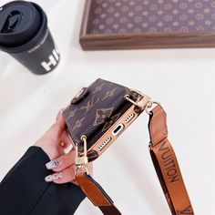 a hand holding a brown louis vuitton purse next to a black coffee cup