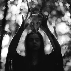 a woman holding up a deer's head in front of her face with two hands