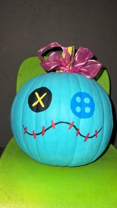 a blue pumpkin with a skull painted on it's face sitting on a green chair