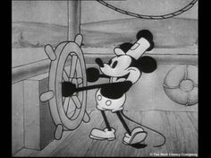 a drawing of mickey mouse standing next to a steering wheel in a room with wood floors