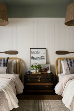 two twin beds in a bedroom with white walls and wood trim on the headboard