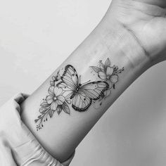 a black and white photo of a butterfly with flowers on its left wrist tattoo design