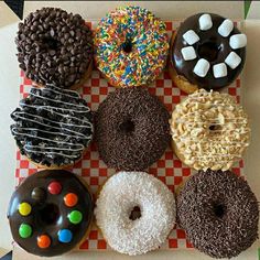 six donuts with different toppings on a checkered tableclothed tray in a box