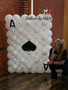 a woman sitting on the floor next to a giant balloon wall with a ace playing card