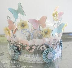 a tiara with flowers and butterflies on it sitting on a table next to a wall