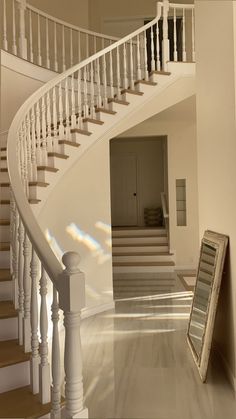 a white staircase leading to a second story with a mirror on the floor next to it