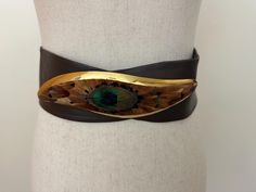 This 1980s leather belt features a distinctive peacock feather buckle, showcasing a vibrant, iridescent design reminiscent of the era's bold fashion. The buckle, adorned with intricate feather details in rich blues and greens, adds a touch of vintage elegance and flair to the classic leather strap. Perfect for adding a unique, retro touch to any outfit. Fits a modern size small or medium. Iridescent Design, Blues And Greens, Tacoma Wa, Vintage Elegance, Suspender Belt, Peacock Feather, 1980s Vintage, Classic Leather, Bold Fashion