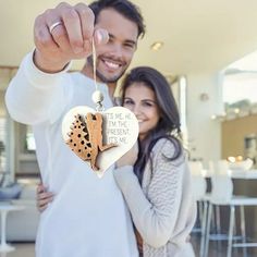 a man and woman holding up a heart shaped ornament that says, i'm the present me