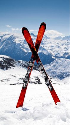 two skis sticking out of the snow on top of a mountain with mountains in the background