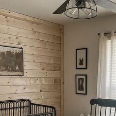 a baby crib in a room with wood paneling on the walls and pictures hanging on the wall