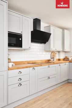 a kitchen with white cabinets and wood counter tops