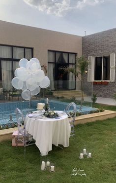 a table set up with balloons in the shape of flowers and candles for an outdoor party