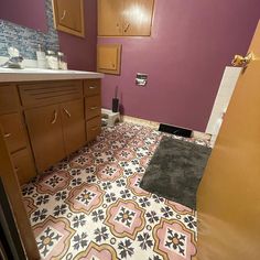 a bathroom with purple walls and brown cabinets