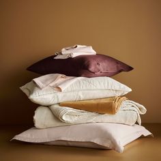 pillows stacked on top of each other in front of a brown wall and tan background