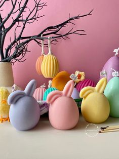 several different colored plastic easter eggs in front of a tree with pencils on it