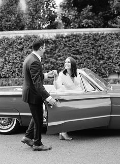 a man standing next to a woman in front of a car