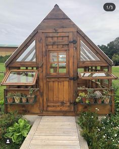 a small wooden house sitting on top of a lush green field next to a walkway