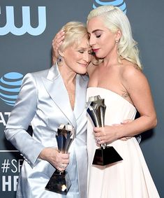 two women hugging each other while holding trophies