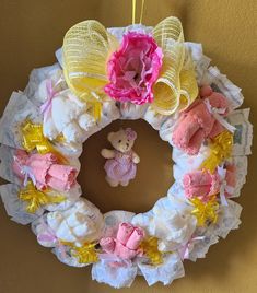 a wreath made out of diaper and fabric with a teddy bear hanging from it