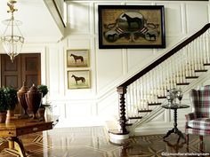 a room with some chairs and pictures on the wall next to a stair case in front of a table