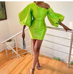 a woman in a neon green dress is walking down the stairs with her hands on her hips