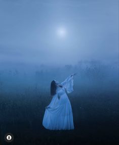 a woman in a white dress is standing in the fog