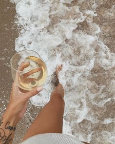 a person holding a glass of wine on the beach