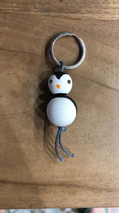 a penguin keychain hanging from a wooden table