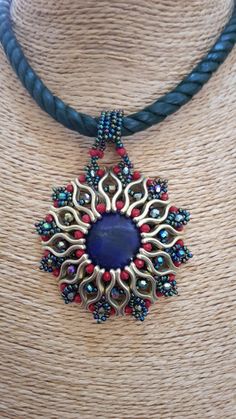 a necklace with a blue stone surrounded by multicolored beads on a leather cord