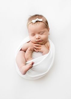 a baby wrapped in a white wrap is laying on it's side with its eyes closed