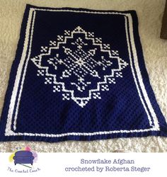 a crocheted afghan is laying on the floor in front of a white carpet